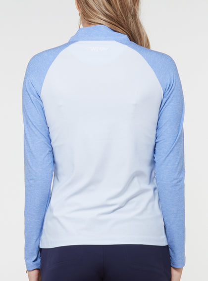 Back view of a woman wearing a light blue quarter-zip pullover with contrasting blue raglan sleeves, light body, and high collar
