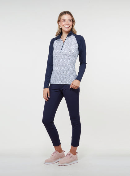 Straight Down Women's Daizee Quarter Zip in New Indigo, on model full length view showing white floral print body with navy raglan sleeves paired with navy pants and pink golf shoes