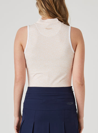 Orchard Sleeveless Polo in Bellini, back view on model featuring a peach sleeveless polo with an allover white delicate leaf and vine print, white armhole trim, and Straight Down logo at the upper back, paired with a navy pleated skort