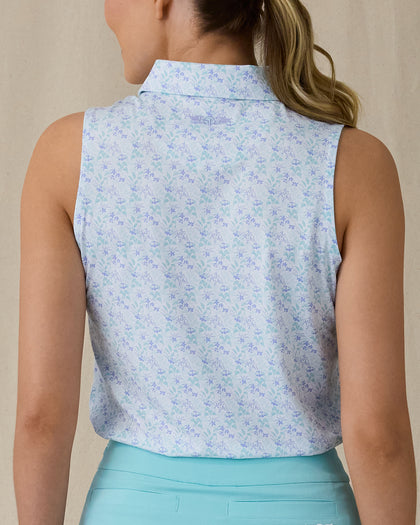 Women's Costa Rica Sleeveless Polo in Green Stone, back on-model view featuring a white sleeveless polo with an allover small floral and leaf print in blue and mint green tones, spread collar, and Straight Down logo embroidered at the upper back, paired with a mint green skirt