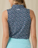 Women's Flores Sleeveless Polo in New Indigo, back on-model view featuring a navy sleeveless polo with an allover small floral print in white and mint green tones, spread collar, and Straight Down logo embroidered at the upper back, paired with a mint green skirt