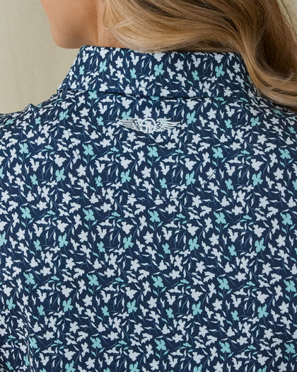 Women's Flores Sleeveless Polo in New Indigo, close-up back on-model view highlighting the Straight Down logo embroidered at the upper back featuring an allover small floral print in white and mint green tones on a navy base