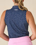 Cherry Bloom Sleeveless Polo in New Indigo, back view on model featuring a navy base with scattered white and pink floral print and Straight Down logo embroidered at center back, paired with a pink skort