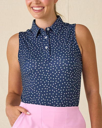Cherry Bloom Sleeveless Polo in New Indigo, front view on model featuring a navy base with scattered white and pink floral print, paired with a pink skort