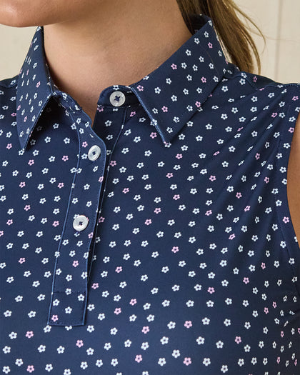 Cherry Bloom Sleeveless Polo in New Indigo, close-up detail view on model featuring a navy base with scattered white and pink floral print