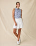 Moloka'i Sleeveless Polo in Moonlight, full-length front angle view on model featuring a slate blue base with a white hibiscus and tropical leaf print, paired with a white skort and white golf shoes