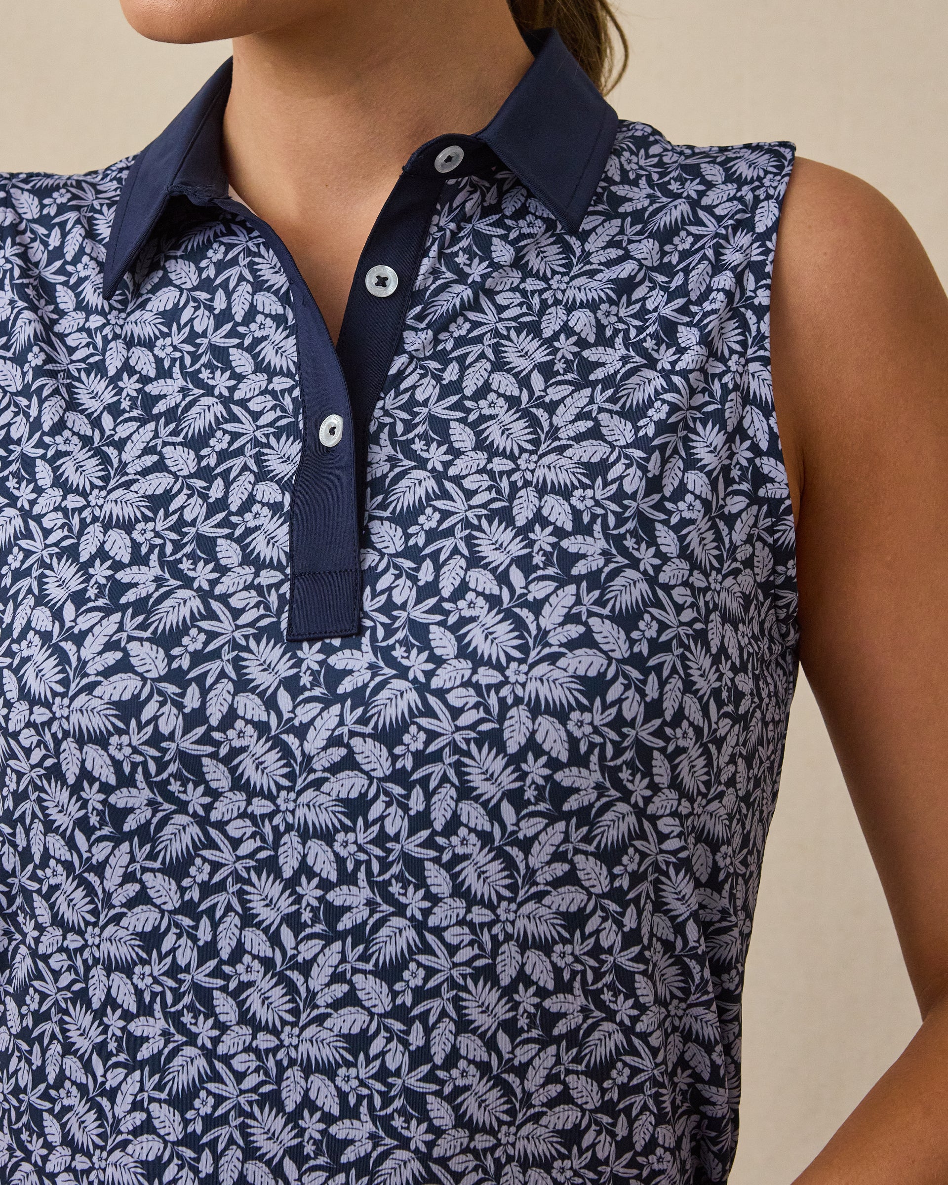 Close-up of the Women's Huli Sleeveless Polo in New Indigo featuring a detailed tropical leaf and floral print with a contrasting solid indigo collar and placket