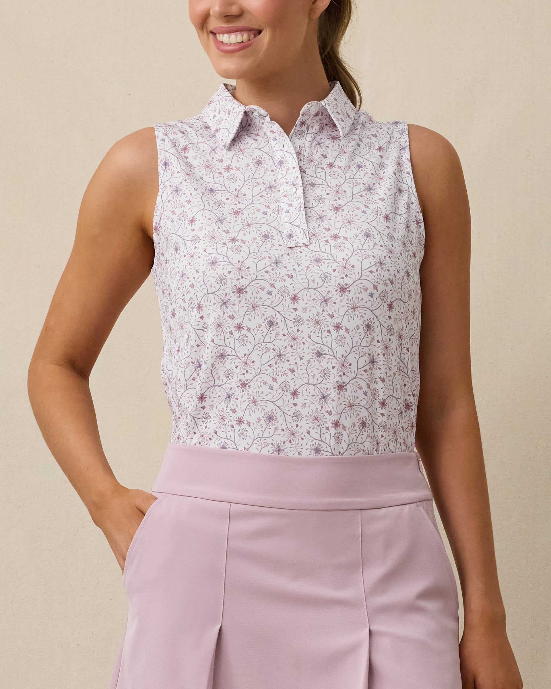 Model wearing the Women's Erika Sleeveless Polo in White with a delicate pink and lavender floral vine print
