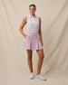 Model wearing the Women's Erika Sleeveless Polo in White tucked into a blush pink pleated golf skort