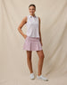 Model wearing the Women's Erika Sleeveless Polo in White untucked with a blush pink pleated golf skort