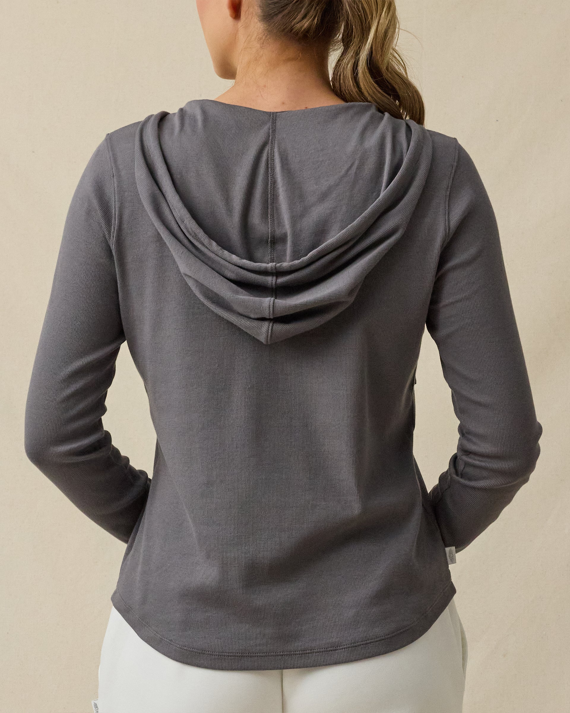 Back view of a woman wearing the Thyme Hoodie in Nightshade, highlighting the relaxed hood and long-sleeve silhouette.