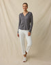 Full-length view of a woman wearing the Thyme Hoodie in Nightshade with white pants and sneakers.