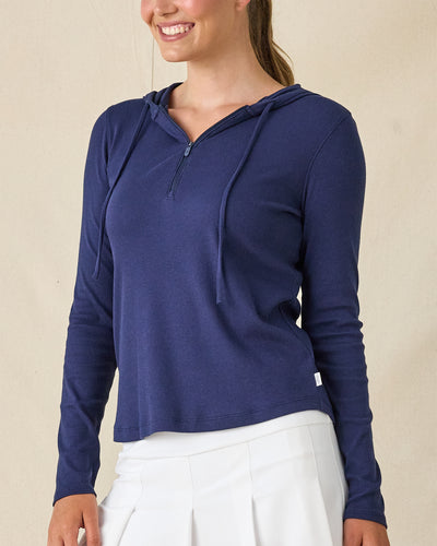 Thyme Quarter Zip Hoodie in New Indigo, front view on model in solid navy ribbed texture with quarter zip and drawstring hood, paired with a white pleated skort