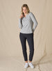 Women’s light grey long sleeve henley top with soft knit fabric, full body front view on model with button placket neckline, and ribbed cuff paired with black pants and white shoes