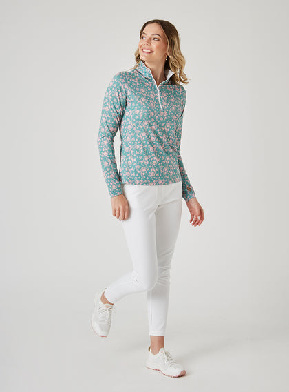 Women's Ava Quarter Zip in Sea Green, full-length front model view featuring a teal long-sleeve pullover with an all-over pink floral vine print styled with white pants and white shoes