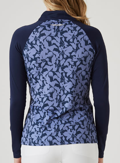 Mabel Quarter Zip in New Indigo, back model view featuring a long-sleeve pullover with an allover navy and blue abstract floral print body, solid navy raglan sleeves, and Straight Down logo at the upper back neckline, paired with white pants