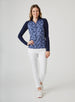 Mabel Quarter Zip in New Indigo, full-length front model view featuring a long-sleeve pullover with an allover navy and blue abstract floral print body, solid navy raglan sleeves, quarter zip, and navy mock neck collar, paired with white cropped pants and white shoes