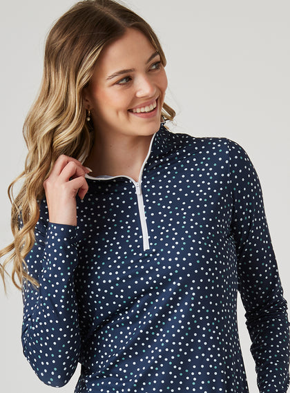 Women's Galaxy Quarter Zip in New Indigo, front model close-up view highlighting the quarter-zip closure, contrast white zipper pull, and white interior collar lining against the navy scattered white and teal polka dot print fabric