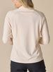 Women's Ellen Quarter Zip in Peche, back view on model featuring a soft peach textured performance fabric with raglan sleeve construction and tonal Straight Down logo at the upper back, paired with black pants