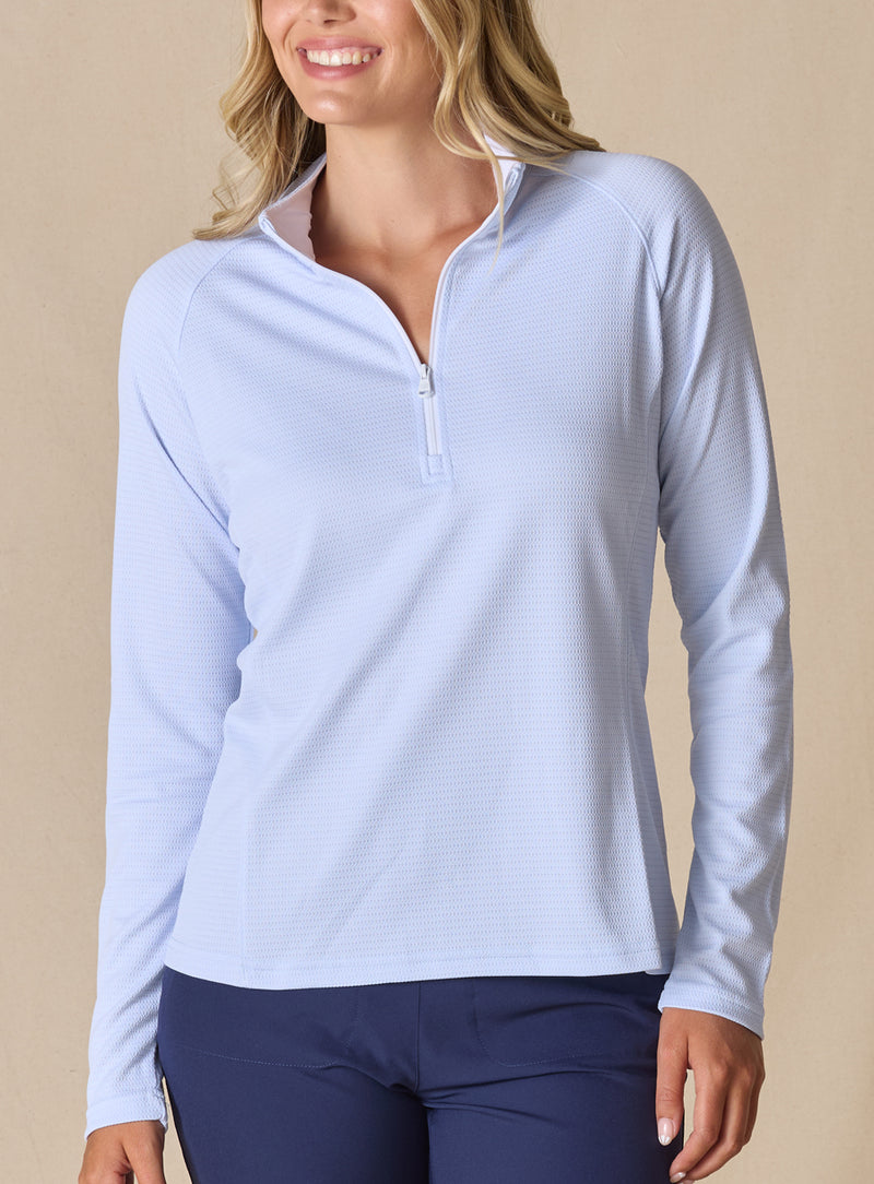 Women's Ellen Quarter Zip in Powder, front view on model featuring a soft powder blue textured performance fabric with a quarter-zip collar, raglan sleeves, and white zipper detail, paired with navy pants