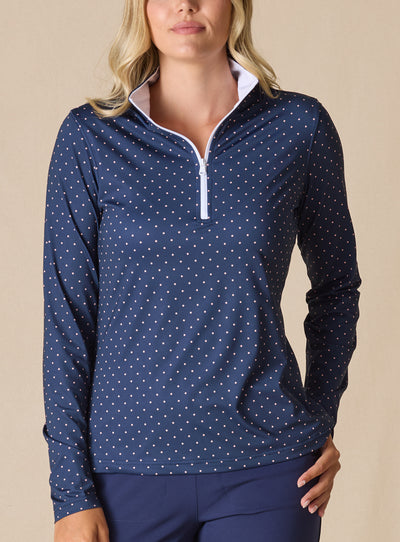 Dottie Quarter Zip in Cedar, front model view featuring a navy long-sleeve pullover with an allover pink polka dot print, quarter zip, and white mock neck collar with white interior lining, paired with navy pants