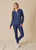 Dottie Quarter Zip in Cedar, full-length front model view featuring a navy long-sleeve pullover with an allover pink polka dot print, quarter zip, and white mock neck collar with white interior lining, paired with navy cropped pants and white shoes
