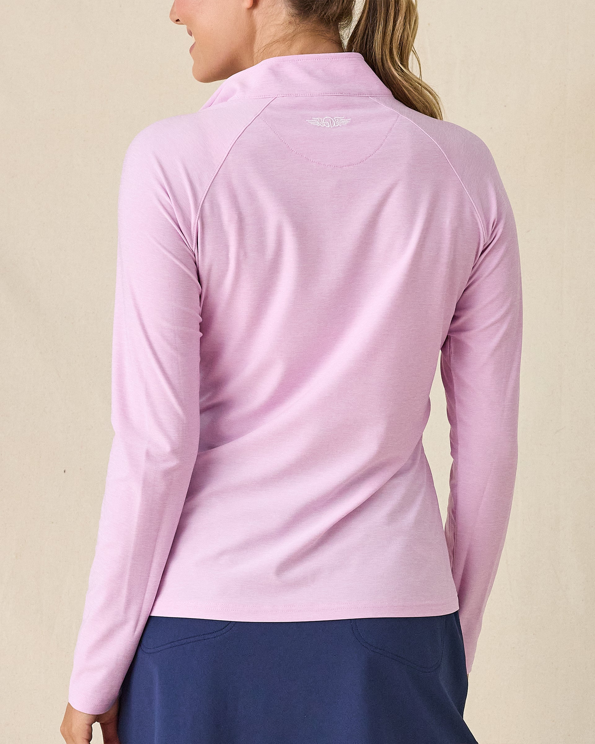 Clara Quarter Zip in Pink Floyd, back view on model in solid light pink with Straight Down logo embroidered at center back, paired with a navy skort