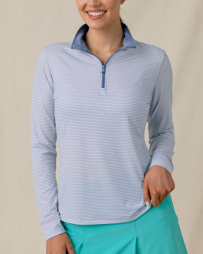 Model wearing the Kiri Stripe Quarter Zip in Tidal Blue with aqua golf skort, front view