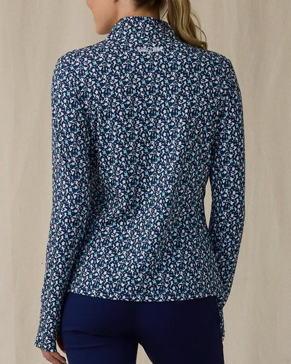 Women's Flores Quarter Zip in New Indigo, back on-model view featuring a navy long sleeve quarter zip pullover with an allover small floral print in white and mint green tones, mock neck collar, and Straight Down logo embroidered at the upper back, paired with navy pants