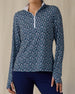 Women's Flores Quarter Zip in New Indigo, front on-model view from the waist up featuring a navy long sleeve quarter zip pullover with an allover small floral print in white and mint green tones, mock neck collar, and white zipper, paired with navy pants