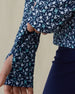 Women's Flores Quarter Zip in New Indigo, close-up on-model view highlighting the thumb hole cuff detail on the long sleeve featuring an allover small floral print in white and mint green tones on a navy base
