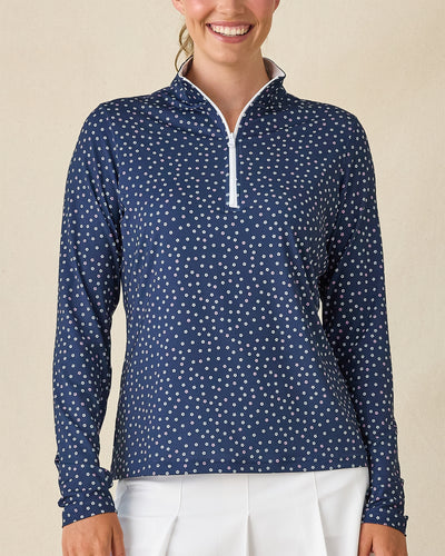 Cherry Bloom Quarter Zip in New Indigo, front close-up view on model featuring a navy base with a scattered white and pink floral print and white quarter zip and white collar interior, paired with white pants