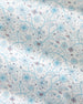 A close-up of a fabric or wallpaper pattern featuring delicate blue and reddish-brown floral vines on a warm off-white background.