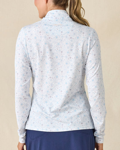 Mariette Quarter Zip in Gemstone, back view featuring a white base with light blue and mauve floral vine allover print pattern with Straight Down embroidered logo at the upper back, paired with navy pants