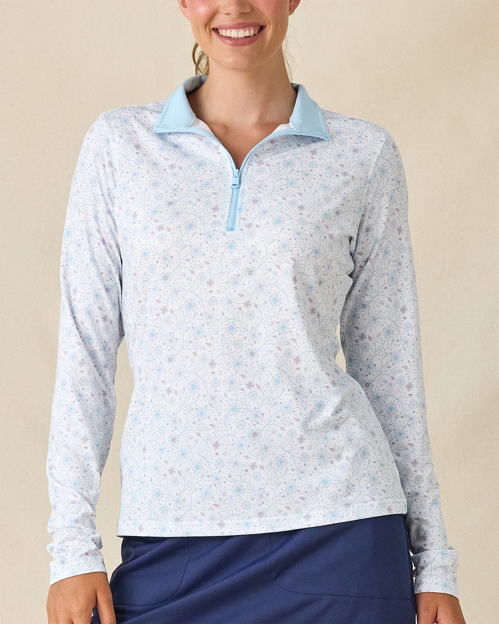 Mariette Quarter Zip in Gemstone, front view featuring a white base with light blue and mauve floral vine allover print pattern and light blue quarter zip with light blue contrast collar lining, paired with navy pants