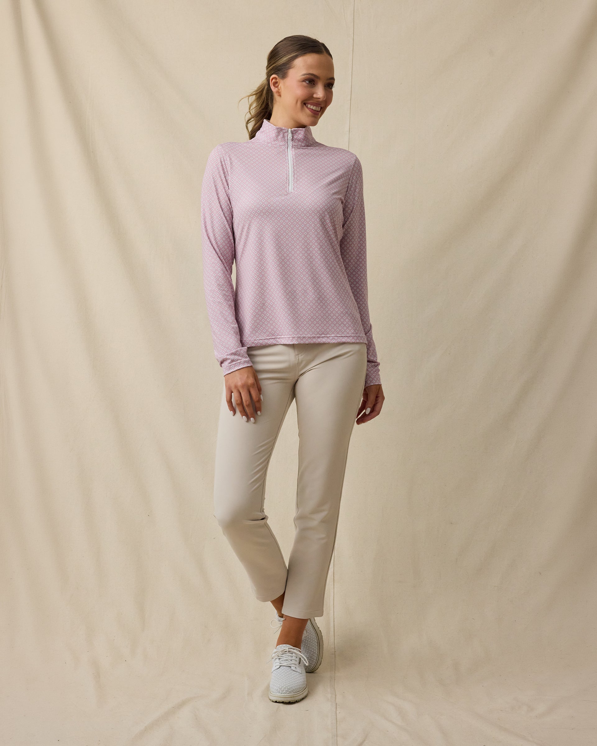 Model wearing the Empress Quarter Zip in Pink Dawn paired with beige golf pants