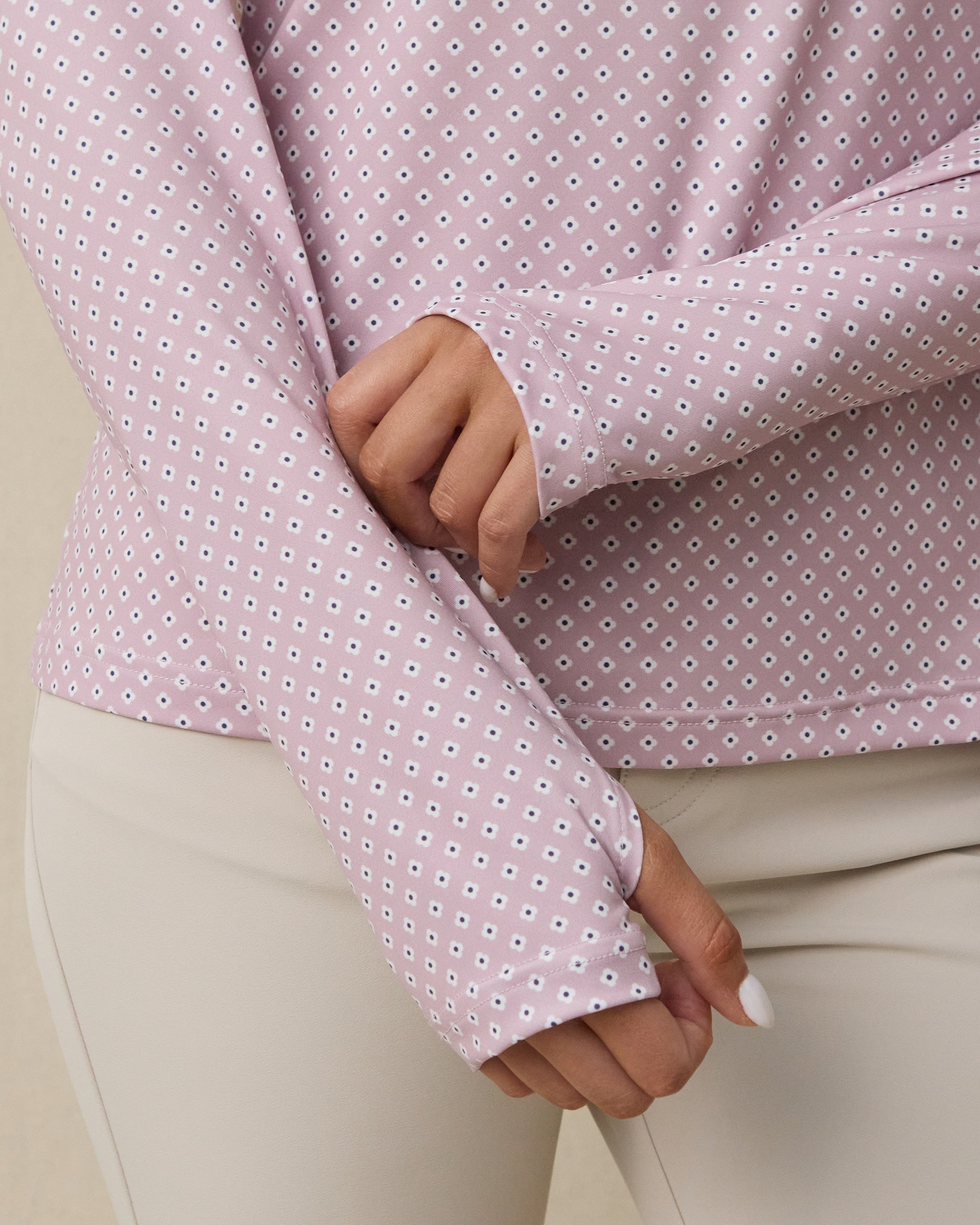 Close-up of the Empress Quarter Zip in Pink Dawn showing the geometric floral print and thumbhole cuff detail