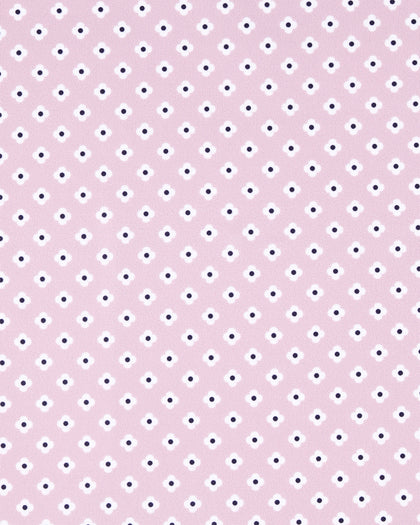 A close-up of a light pink fabric or material with a repeating pattern of small white and dark navy dots.