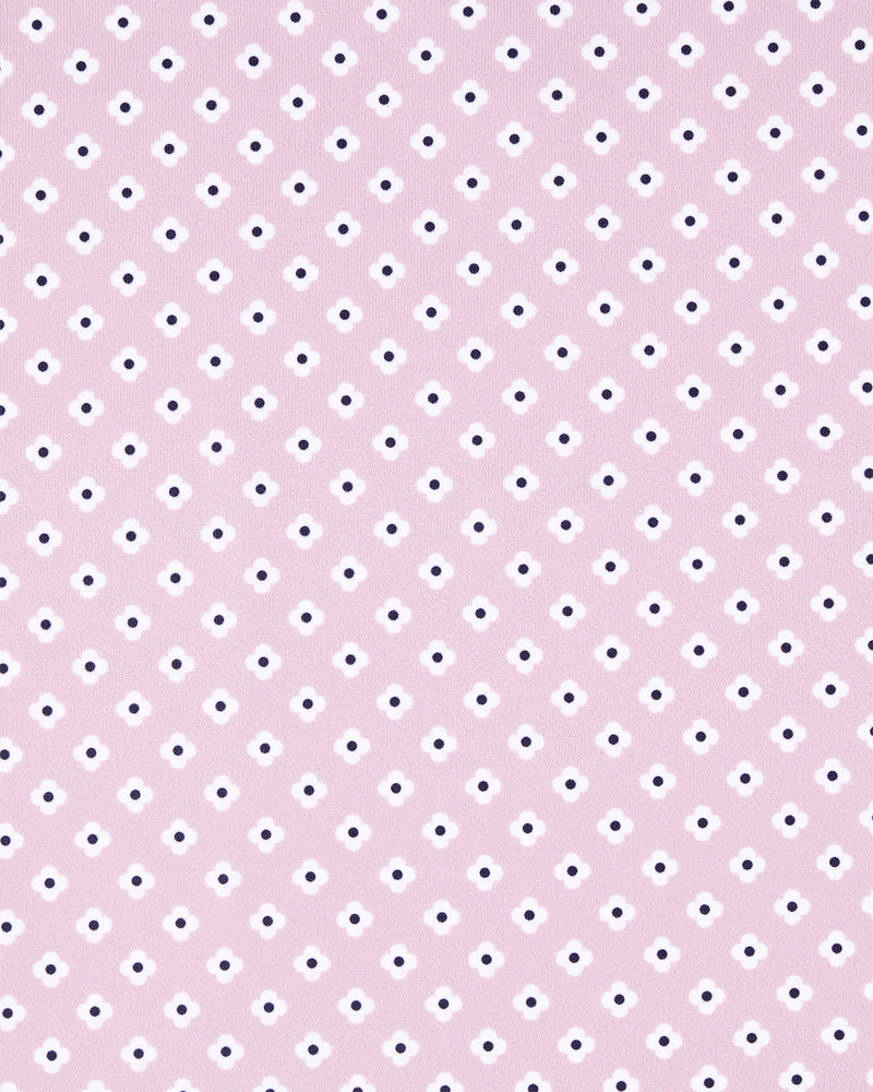 A close-up of a light pink fabric or material with a repeating pattern of small white and dark navy dots.