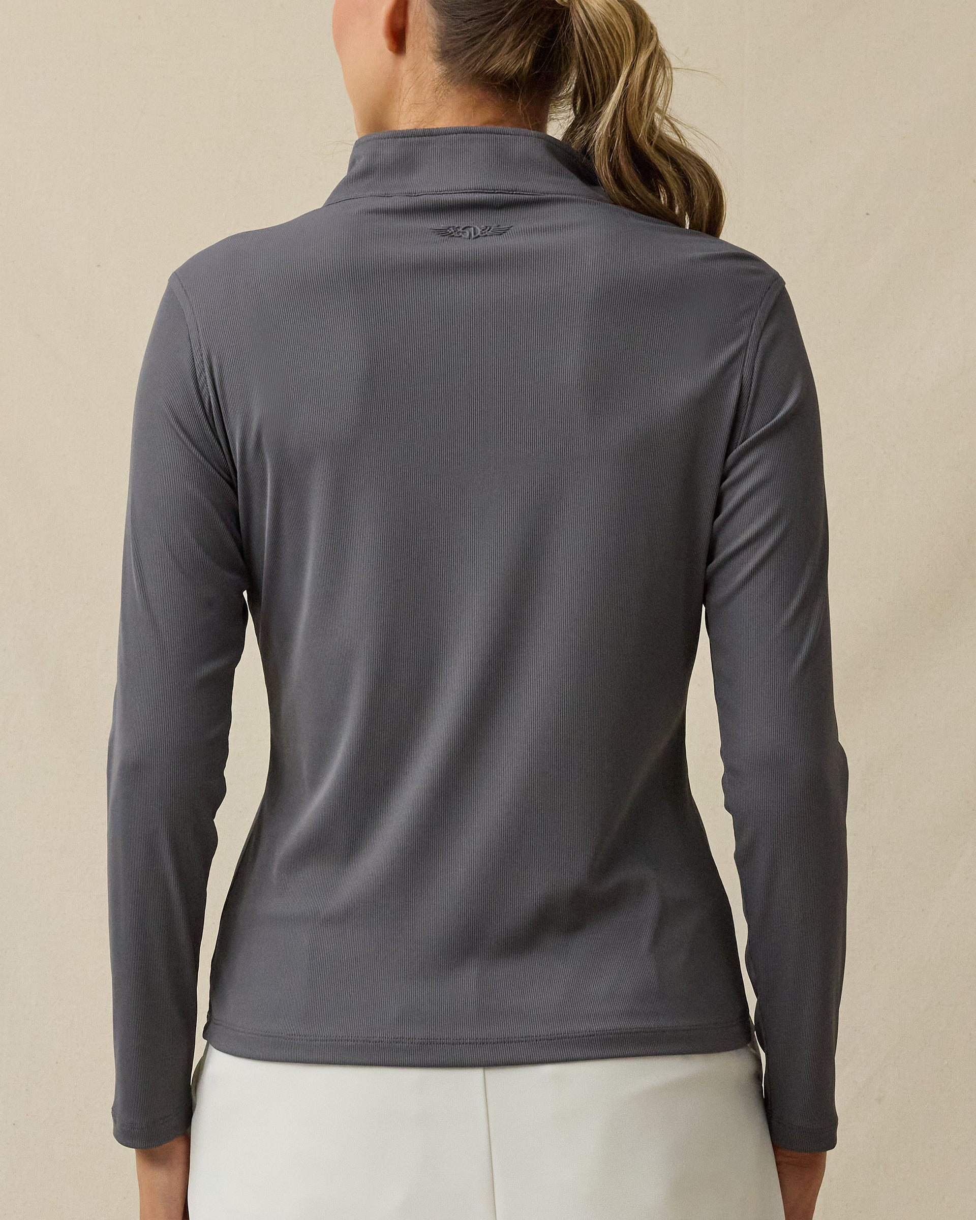 Back view of a woman wearing the Skyler Quarter Zip in Nightshade, showing the ribbed texture and tonal embroidered logo below the back collar.