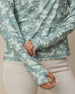 Close-up of the lighter and darker green camouflage top showing the long sleeves and extended cuffs with thumbholes.