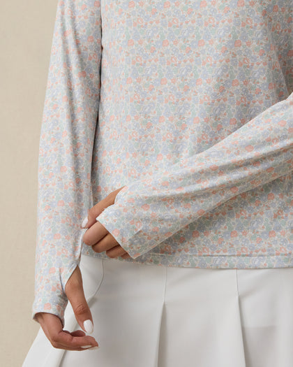 Close-up of the light blue floral long-sleeve top showing the pastel pink, blue, and green flower pattern and extended cuffs with thumbholes.
