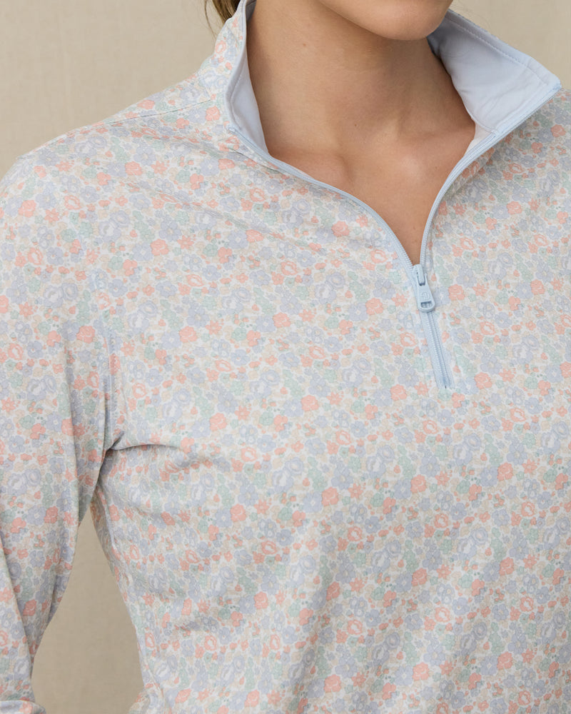 Close-up of the light blue floral quarter-zip top showing the pastel flower print, light blue zipper, and contrasting stand collar.