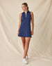 Greta Dress in New Indigo, full length front view on model showing a navy sleeveless polo dress with a quarter zip neckline and front patch pockets, paired with white golf shoes
