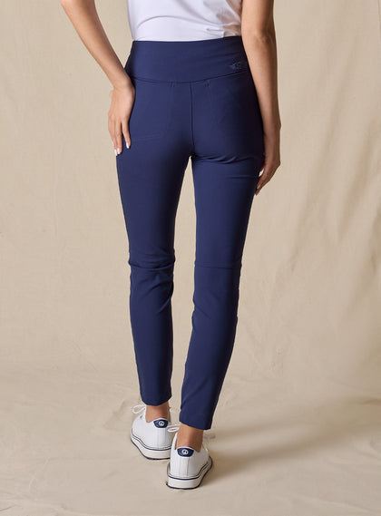Lexi Pant in New Indigo, back view on model featuring solid navy fabric with wide waistband, back pockets, and tonal Straight Down logo embroidery styled with a white top and white shoes
