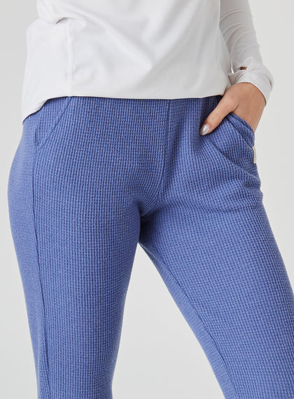 Women's Mavis Jogger in Blueberry, close-up model view featuring a medium blue waffle-knit jogger with elasticated waistband, front seam detail, side pocket, and tonal Straight Down logo patch