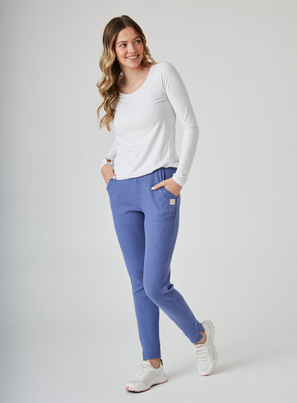 Women's Mavis Jogger in Blueberry, full length model view featuring a medium blue waffle-knit jogger with elasticated waistband, Straight Down logo patch, and tapered leg with ankle vent detail paired with a white long sleeve top and white athletic shoes