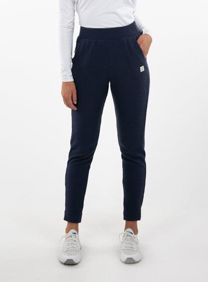 Women's Mavis Jogger in Ink, front model view featuring a navy waffle-knit jogger with elasticated waistband, side pocket with Straight Down logo patch, and ankle vent detail paired with a white long sleeve top and white athletic shoes