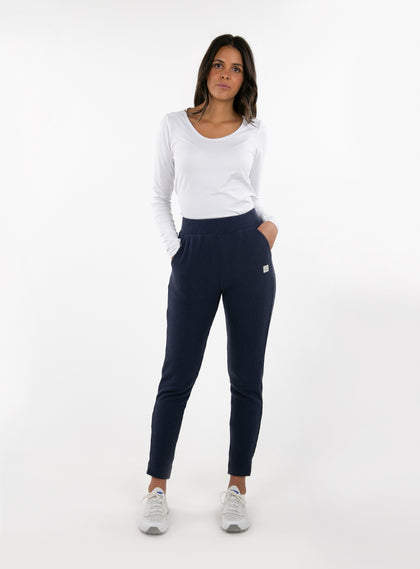 Women's Mavis Jogger in Ink, full length model view featuring a navy waffle-knit jogger with elasticated waistband, Straight Down logo patch, and tapered leg with ankle vent detail paired with a white long sleeve top and white athletic shoes