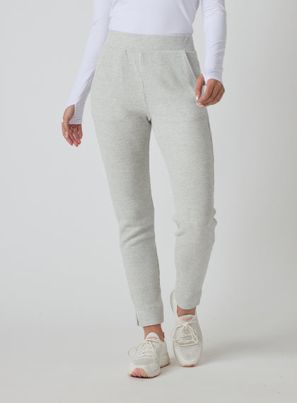 Women's Mavis Jogger in New Heather, front model view featuring a heather grey waffle-knit jogger with elasticated waistband, tapered leg, and ankle vent detail paired with a white long sleeve top and white athletic shoes